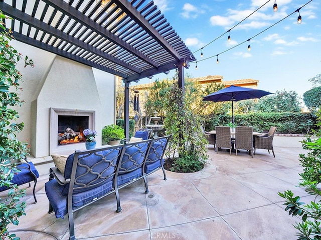 view of patio with outdoor dining space, a pergola, and a large fireplace