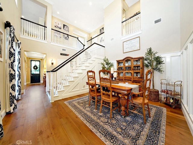 dining space with visible vents, hardwood / wood-style floors, stairs, and a decorative wall