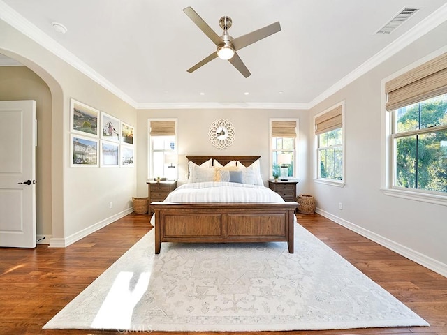 bedroom featuring arched walkways, visible vents, ornamental molding, and wood finished floors