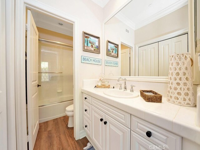 bathroom with visible vents, toilet, ornamental molding, wood finished floors, and vanity