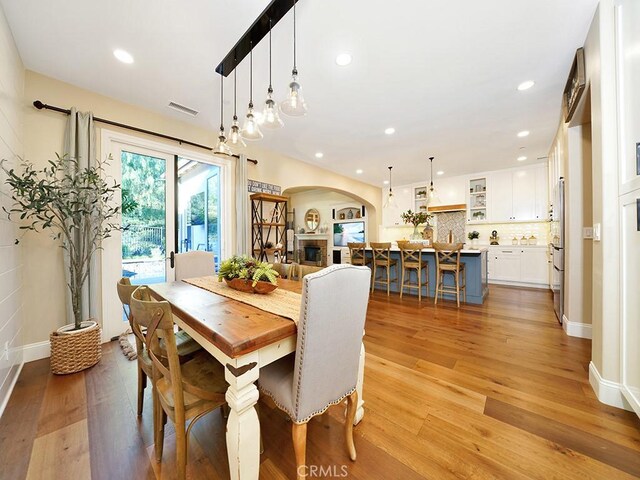 dining space with arched walkways, visible vents, light wood-style flooring, and recessed lighting