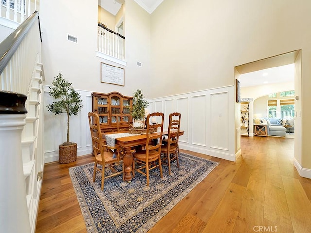 dining area with arched walkways, visible vents, light wood-style flooring, and a decorative wall