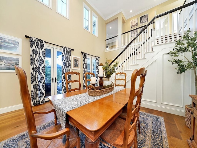 dining room with stairway, wood finished floors, baseboards, ornamental molding, and french doors