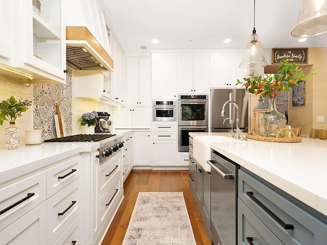 kitchen with gray cabinetry, stainless steel appliances, light countertops, and wood finished floors