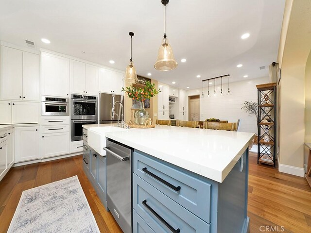 kitchen featuring white cabinets, gray cabinets, stainless steel appliances, and dark wood-style flooring