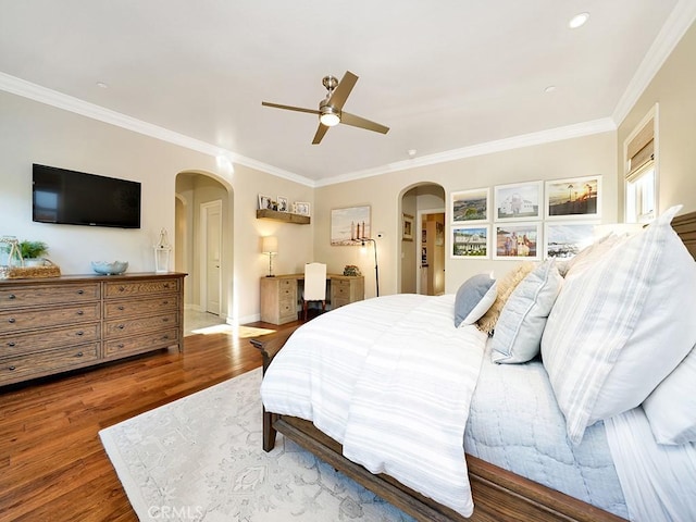 bedroom with a ceiling fan, wood finished floors, arched walkways, crown molding, and baseboards