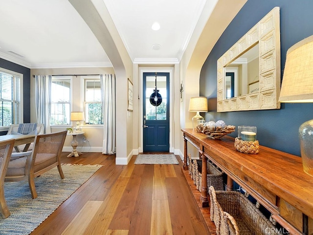 entrance foyer with baseboards, arched walkways, hardwood / wood-style floors, and ornamental molding