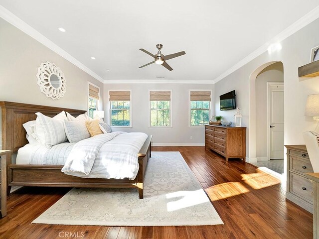 bedroom with a ceiling fan, dark wood finished floors, arched walkways, crown molding, and baseboards