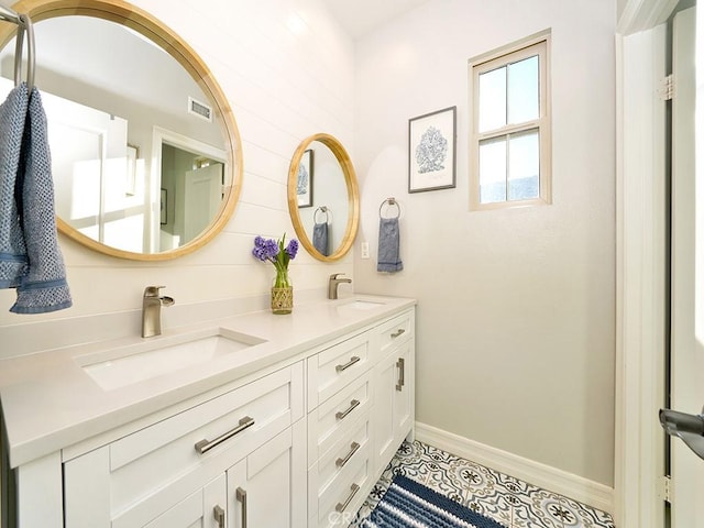 bathroom featuring double vanity, visible vents, baseboards, and a sink