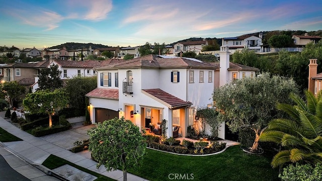 mediterranean / spanish home featuring stucco siding, driveway, a residential view, an attached garage, and a tiled roof