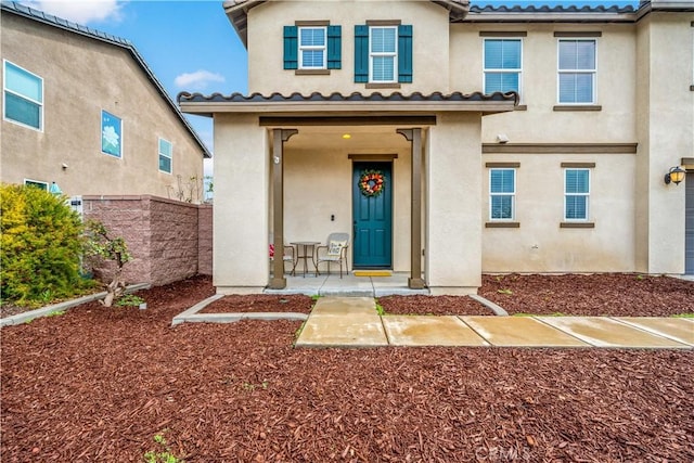 view of front of property featuring stucco siding, a tile roof, and fence