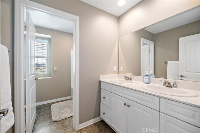 full bathroom with a sink, baseboards, double vanity, and tile patterned floors