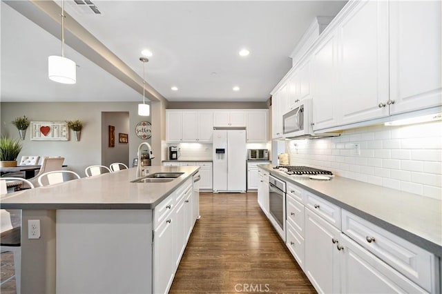 kitchen with visible vents, a sink, appliances with stainless steel finishes, a kitchen bar, and tasteful backsplash