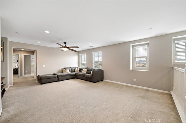 unfurnished living room featuring baseboards, light colored carpet, a healthy amount of sunlight, and a ceiling fan