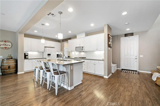 kitchen featuring visible vents, dark wood finished floors, an island with sink, a sink, and stainless steel appliances