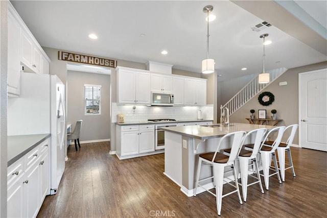 kitchen featuring visible vents, dark wood-type flooring, a sink, appliances with stainless steel finishes, and decorative backsplash