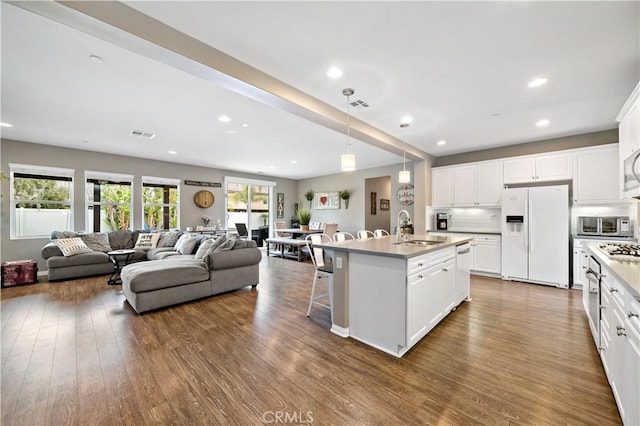 kitchen with dark wood-style flooring, white appliances, visible vents, and a sink