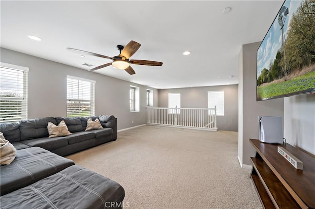 living room featuring light carpet, visible vents, baseboards, and ceiling fan