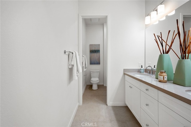 bathroom featuring tile patterned floors, toilet, a sink, double vanity, and baseboards