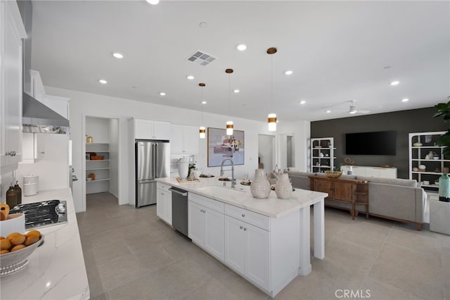 kitchen with visible vents, stainless steel appliances, white cabinetry, wall chimney exhaust hood, and a sink