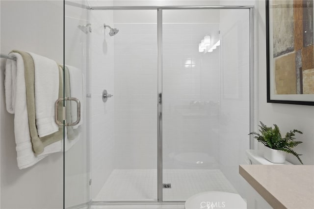 bathroom featuring vanity, a shower stall, and toilet