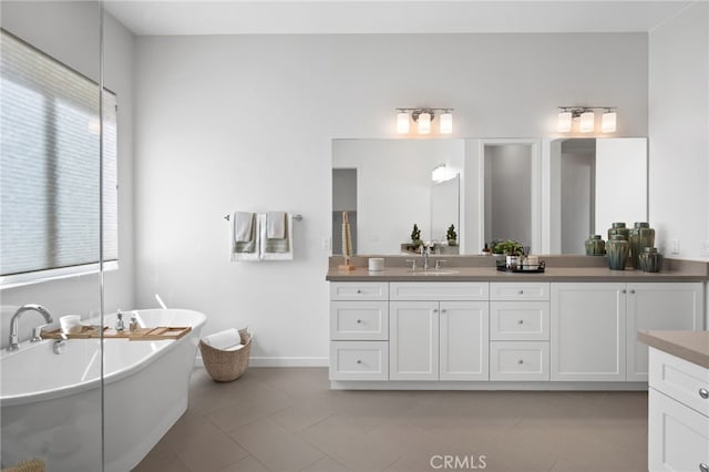 full bathroom featuring vanity, tile patterned floors, baseboards, and a freestanding bath