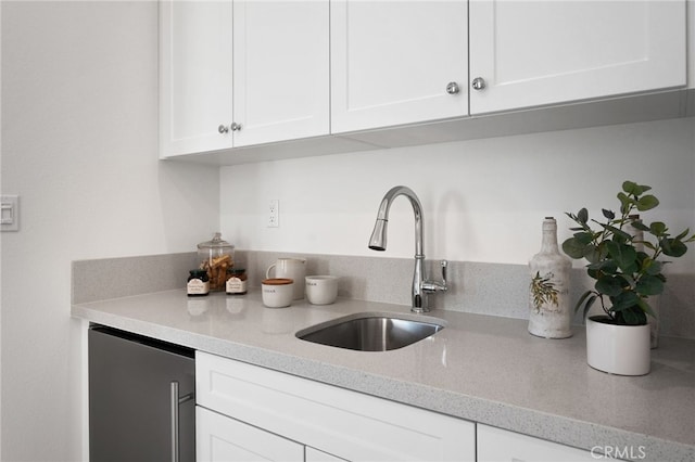 kitchen with refrigerator, light stone countertops, white cabinets, and a sink