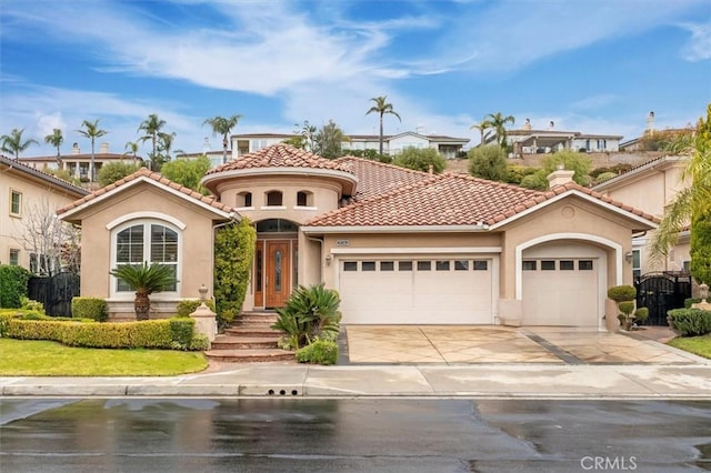 mediterranean / spanish home with a tile roof, an attached garage, driveway, and stucco siding