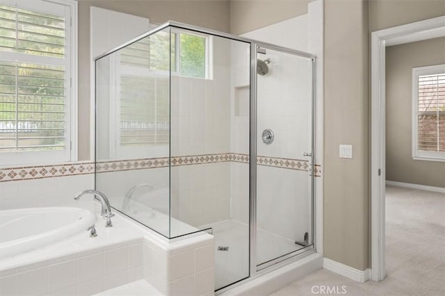 bathroom featuring a shower stall, a garden tub, and baseboards