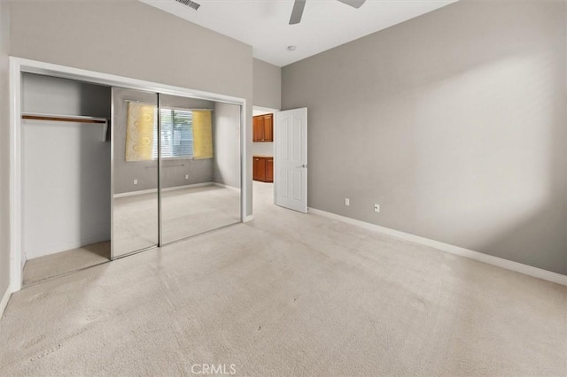 unfurnished bedroom with a closet, baseboards, light colored carpet, and ceiling fan