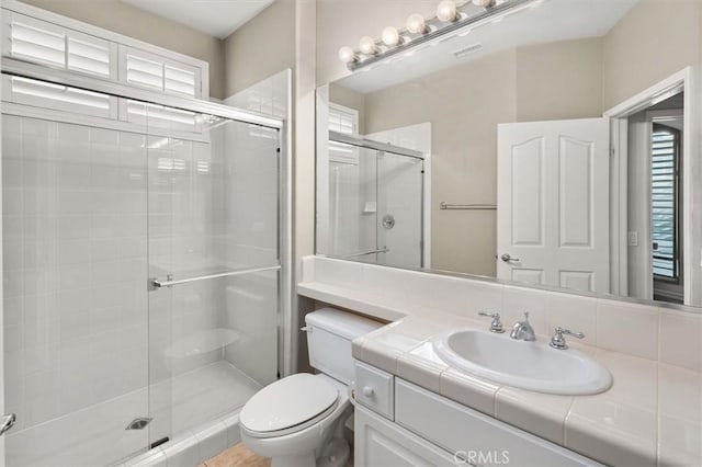 bathroom with a shower stall, toilet, and vanity