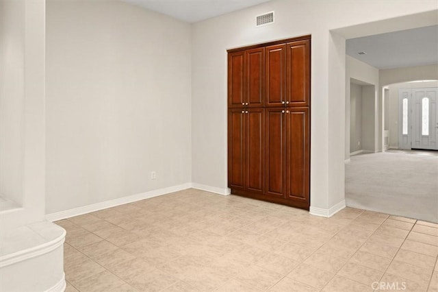 empty room with visible vents, baseboards, light colored carpet, and arched walkways