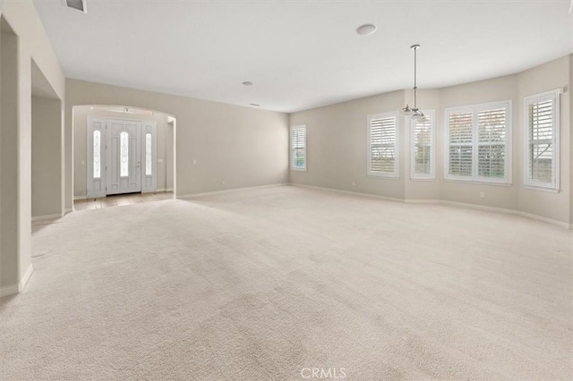 interior space featuring baseboards, arched walkways, and light carpet