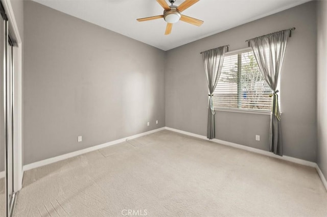 carpeted spare room with a ceiling fan and baseboards