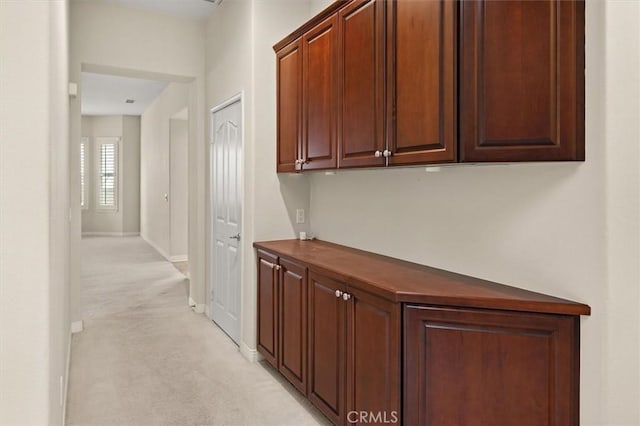 corridor featuring light carpet and baseboards