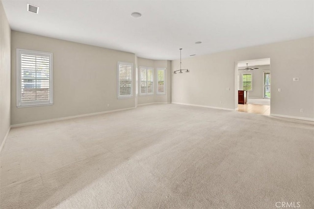 unfurnished room with visible vents, light colored carpet, a ceiling fan, and baseboards