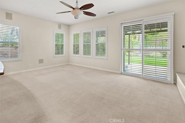 carpeted empty room featuring baseboards, visible vents, and ceiling fan