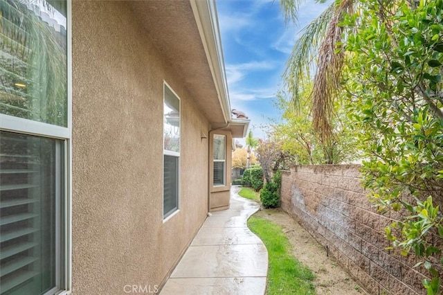 view of home's exterior with stucco siding and fence