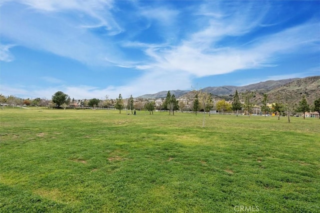 view of home's community with a rural view, a lawn, and a mountain view