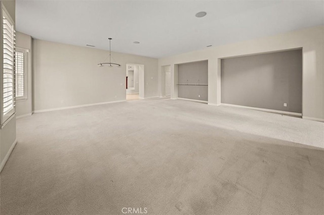 unfurnished living room with baseboards, carpet floors, and a notable chandelier