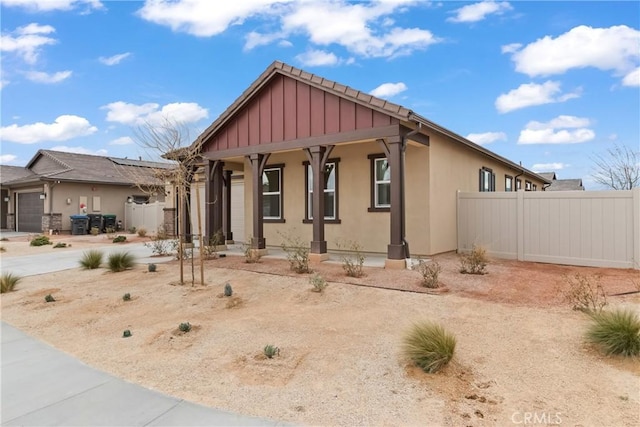 view of front facade with stucco siding, covered porch, and fence