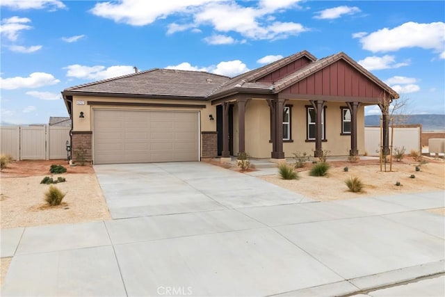 view of front of home with fence, a tiled roof, concrete driveway, stucco siding, and a garage