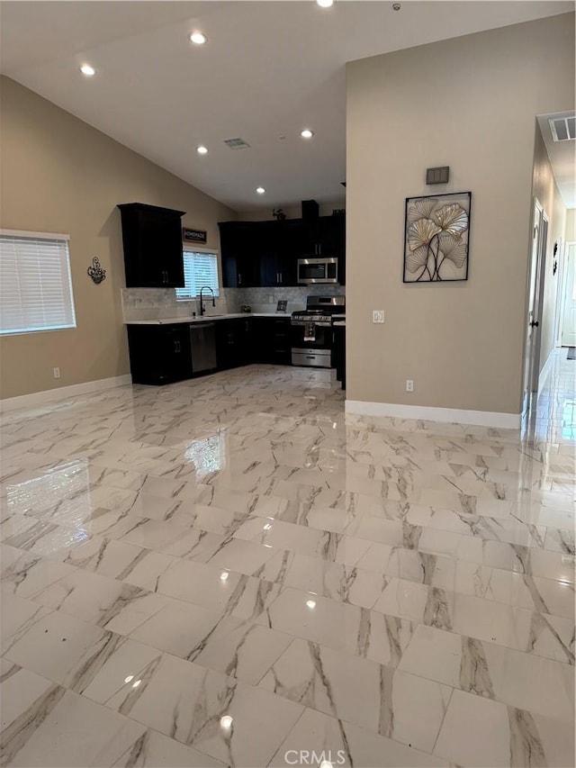 kitchen with dark cabinetry, visible vents, lofted ceiling, light countertops, and appliances with stainless steel finishes