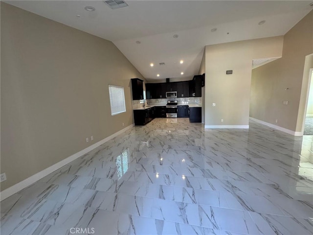 kitchen featuring baseboards, open floor plan, marble finish floor, stainless steel appliances, and dark cabinets