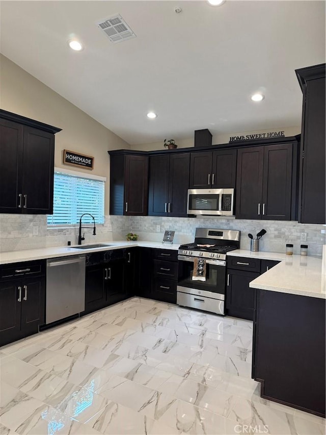 kitchen with visible vents, light countertops, vaulted ceiling, appliances with stainless steel finishes, and a sink