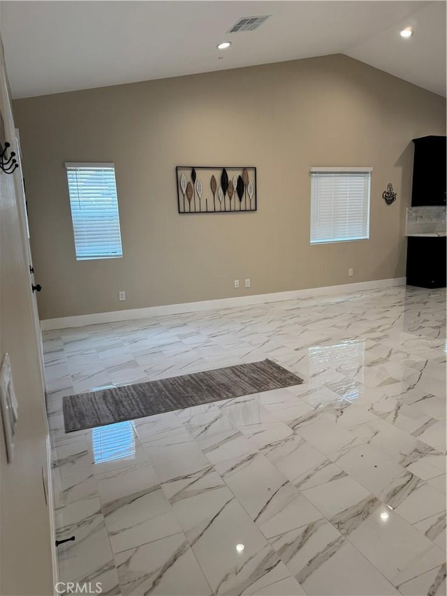 empty room featuring lofted ceiling, baseboards, visible vents, and marble finish floor