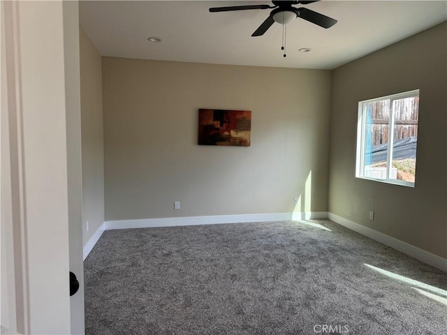 carpeted spare room with a ceiling fan and baseboards