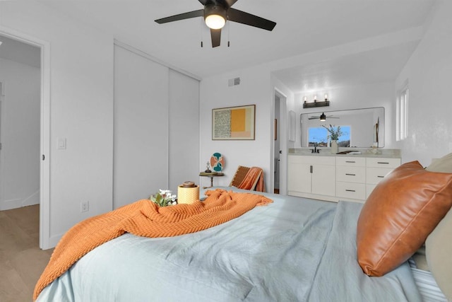 bedroom with a closet, visible vents, a ceiling fan, and a sink