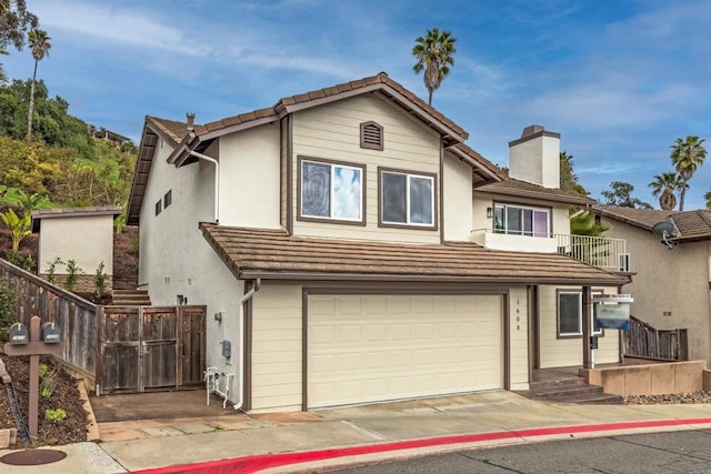 view of front facade featuring fence, stucco siding, a chimney, a balcony, and a garage