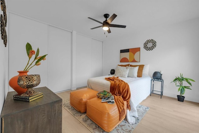 bedroom featuring ceiling fan, multiple closets, and light wood-style flooring